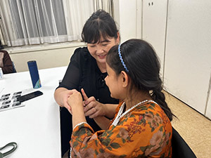 Byamba-san teaching sign language to Mitu-san while holding her hands.